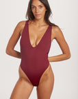 Woman wearing a burgundy swimsuit on a white background