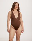 Woman wearing a brown swimsuit on a white background