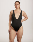 Woman wearing a black swimsuit against a plain background