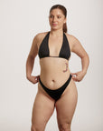Woman wearing a black bikini against a plain background