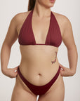 Woman wearing a burgundy bikini against a plain background