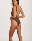 Woman wearing a brown swimsuit with a white background