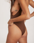 Person wearing a brown swimsuit against a plain background