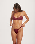 Woman wearing a maroon bra and panties set on a white background