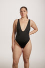 Woman wearing a black swimsuit against a plain background