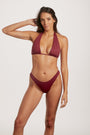 Woman wearing a burgundy bikini against a white background