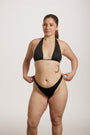 Woman wearing a black bikini against a plain background