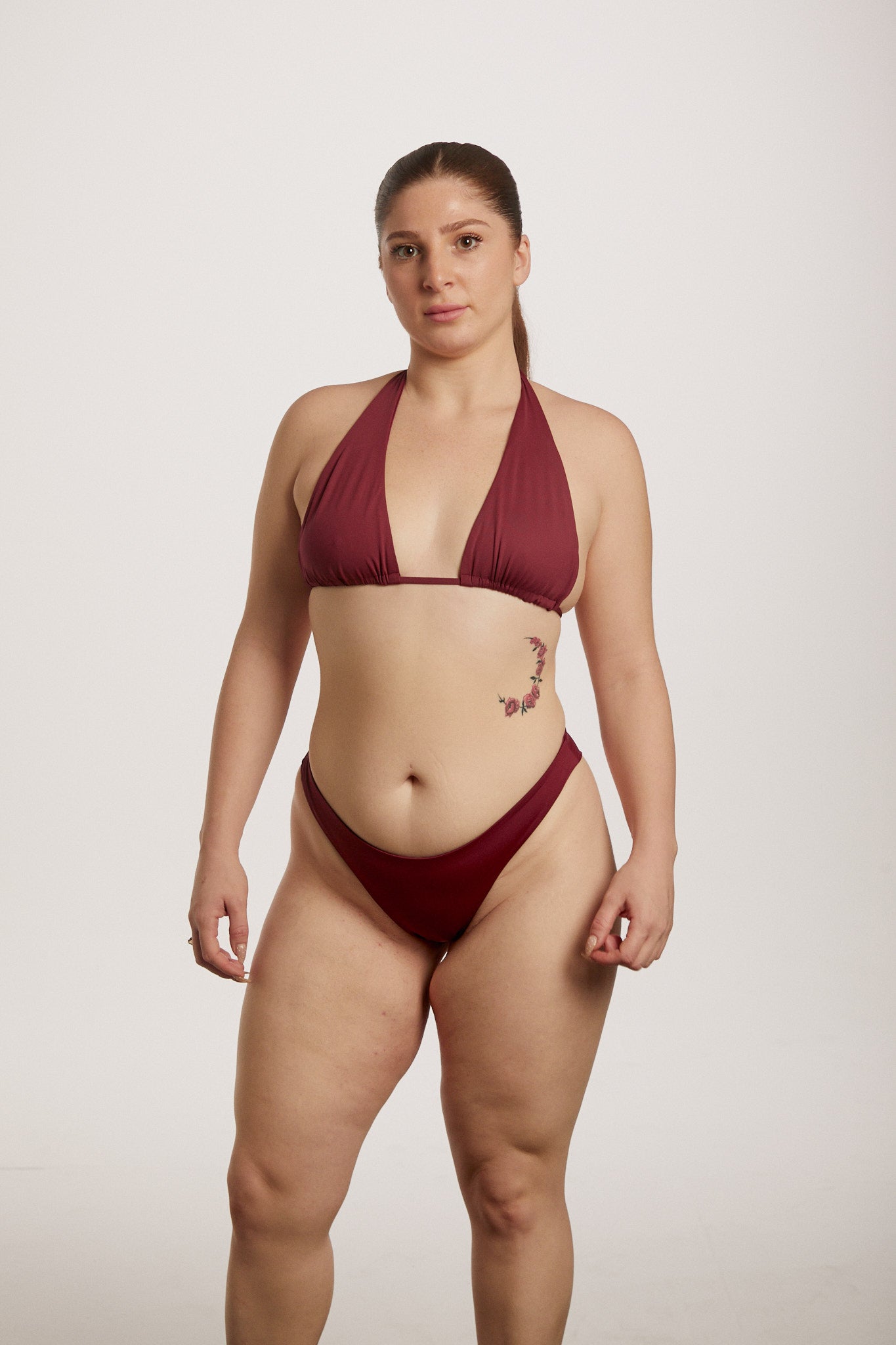 Woman wearing a burgundy bikini against a plain background