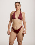 Woman wearing a burgundy bikini against a plain background